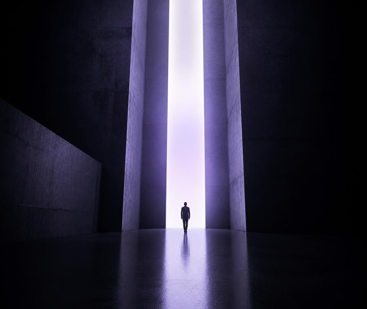 A person walking toward a doorway of light between monumental slabs